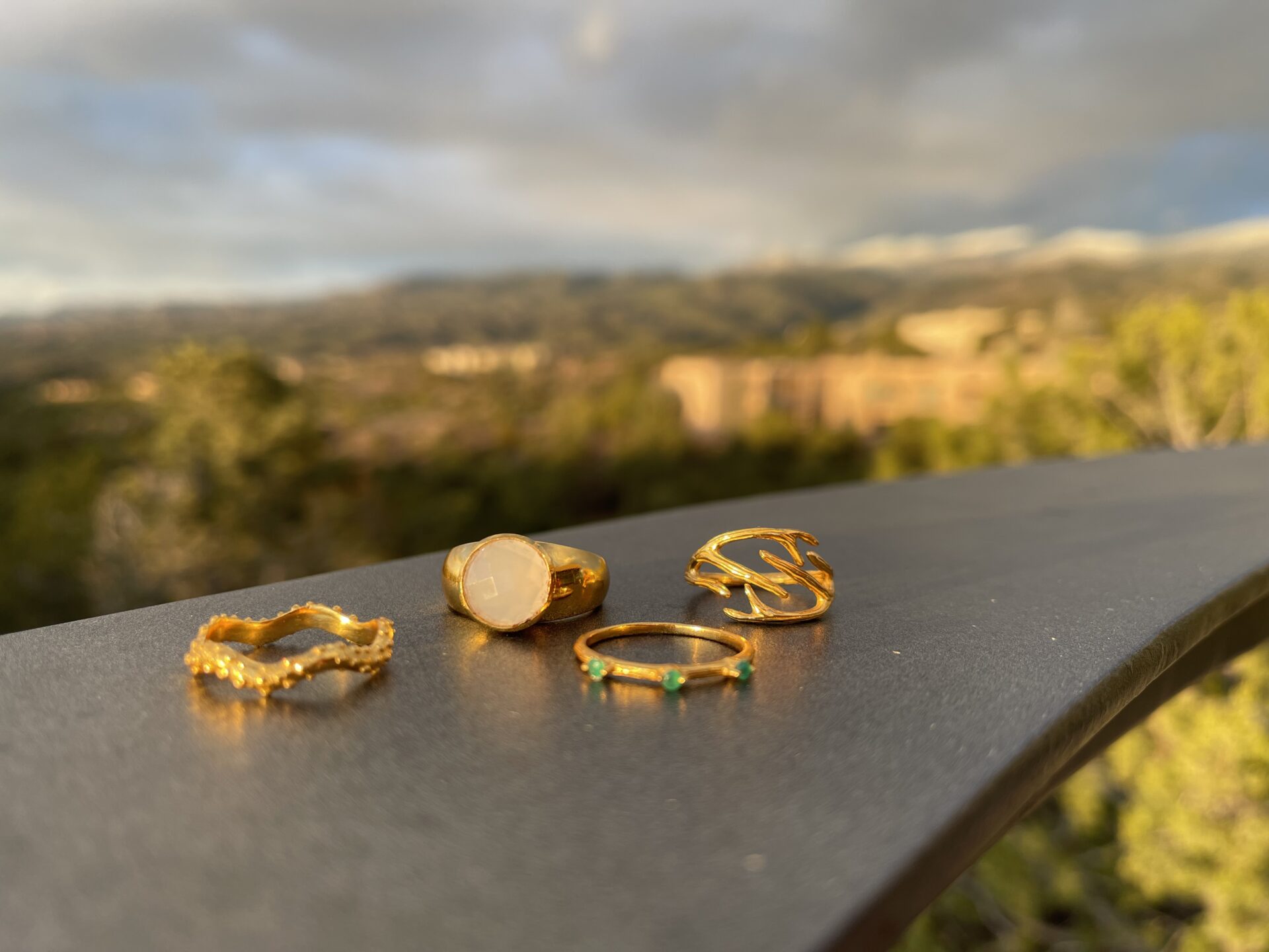 Four rings displayed on a table over looking mountains. 